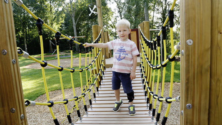 Junge geht mit der WalkOn Reaction junior, einer dynamischen Unterschenkelorthese von Ottobock, auf einer Spielplatz-Hängebrücke