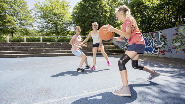 A girl plays basketball with Patella Pro.