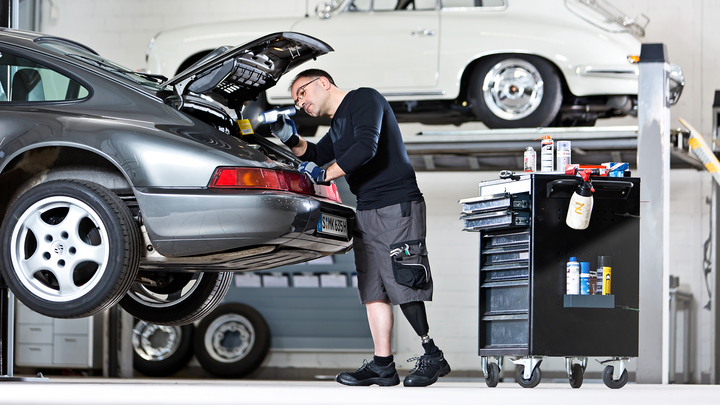 Un homme est debout dans un garage. Il examine le coffre.