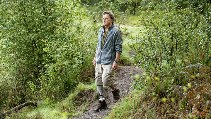 Hans walks down a path in the forest with his Meridium prosthetic foot.