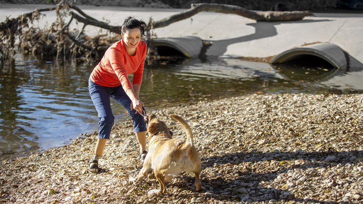 Cassie köpeği ile su kenarında oynuyor.