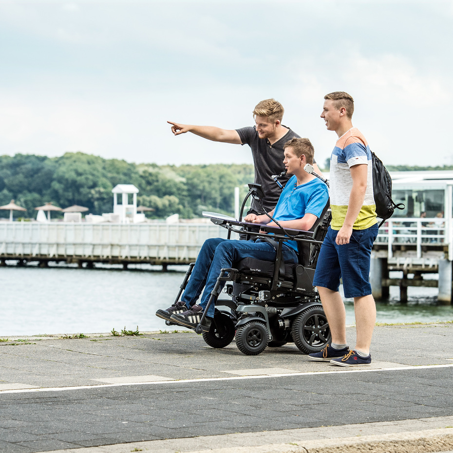 Juvo Ottobock Elektrorollstuhl mit Heckantrieb. Anwender mit zwei Freunden am Hafenbecken und am Schiffe gucken.