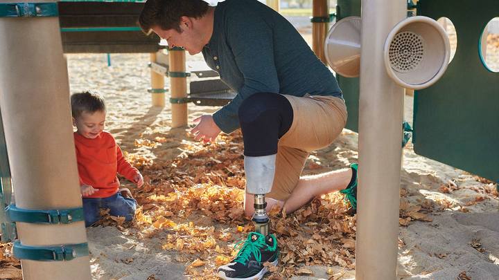 Patient with 3D printed MyFit TT socket kneeling and playing with his son