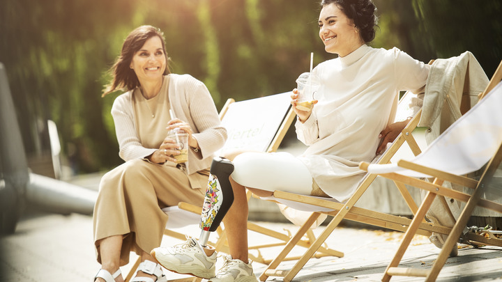 The C-Leg user is sitting at the kitchen table with her friend.