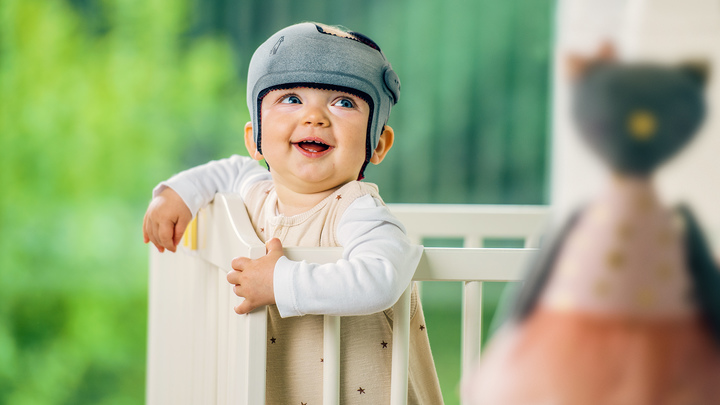 Baby mit einer 3D-gedruckten MyCRO Helm Kranial-Orthese im Kinderbett