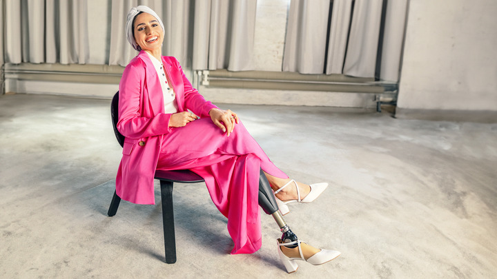 Zainab sitzt mit ihrem Taleo Adjust Prothesenfuß entspannt auf einem Stuhl.