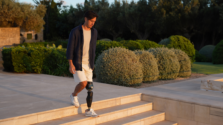 A male user walks down stairs with his Evanto prosthetic foot.