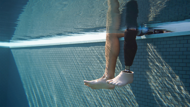 Underwater photo of a prosthetic leg and a natural leg in the pool.