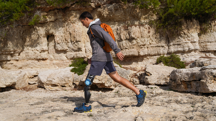 A male user walks over rocky ground with his Ottobock Evanto prosthetic foot.