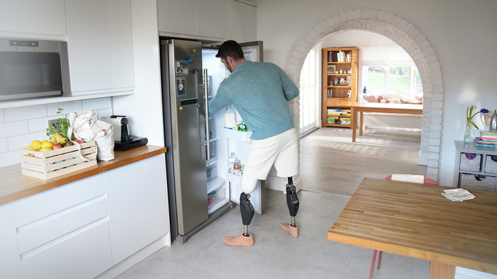 Bilateral Genium X4 user Dave opens the refrigerator and takes a step backwards